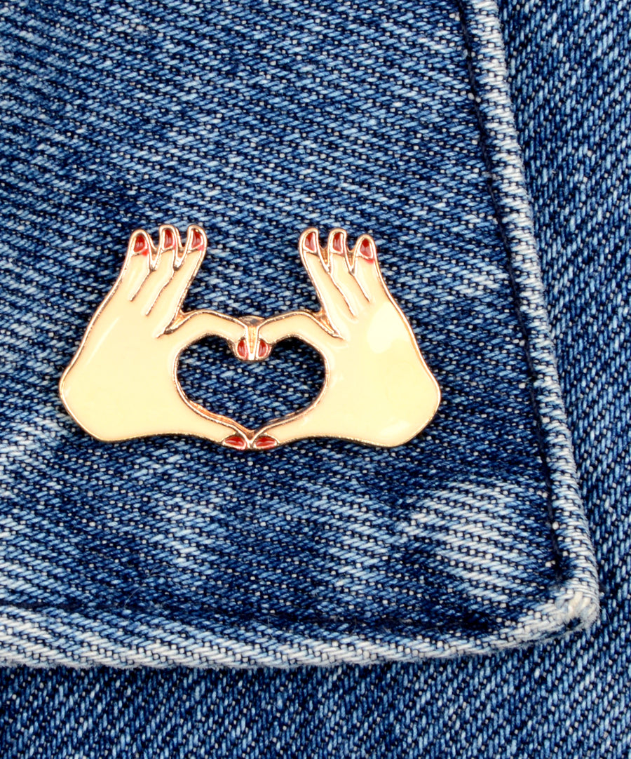 Szívet formázó kezek formájú, pin jellegű kitűző.